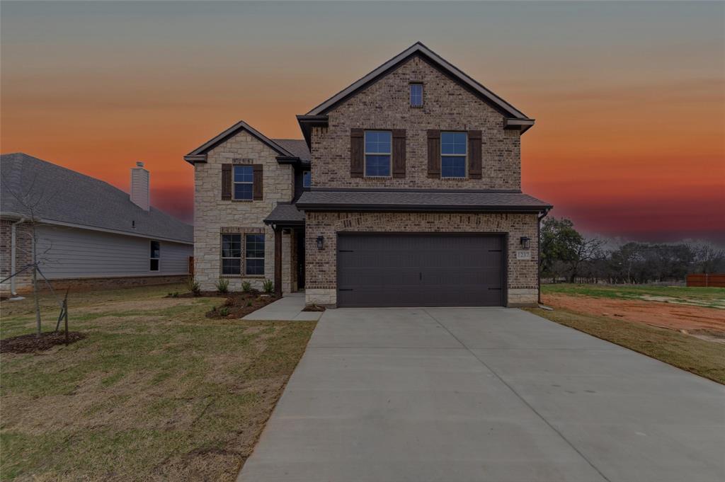 View of front of home featuring a front yard, driveway, brick siding, and a garage