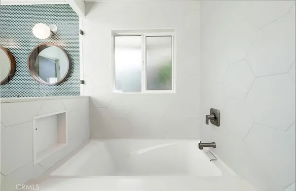 a bathroom with a bathtub a mirror a vanity and a shower