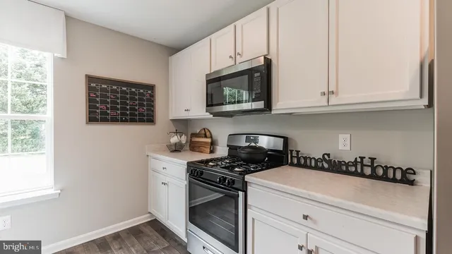 a kitchen with stainless steel appliances granite countertop white cabinets and a stove a oven with white countertops