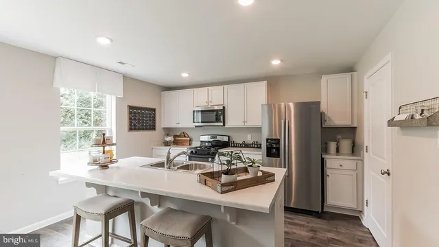 a kitchen with a refrigerator a sink a stove a dining table and chairs