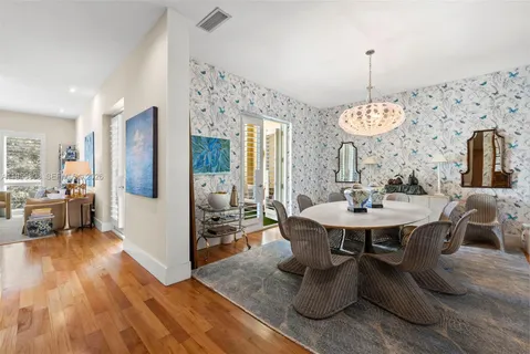 a view of a dining room and livingroom with furniture wooden floor a chandelier
