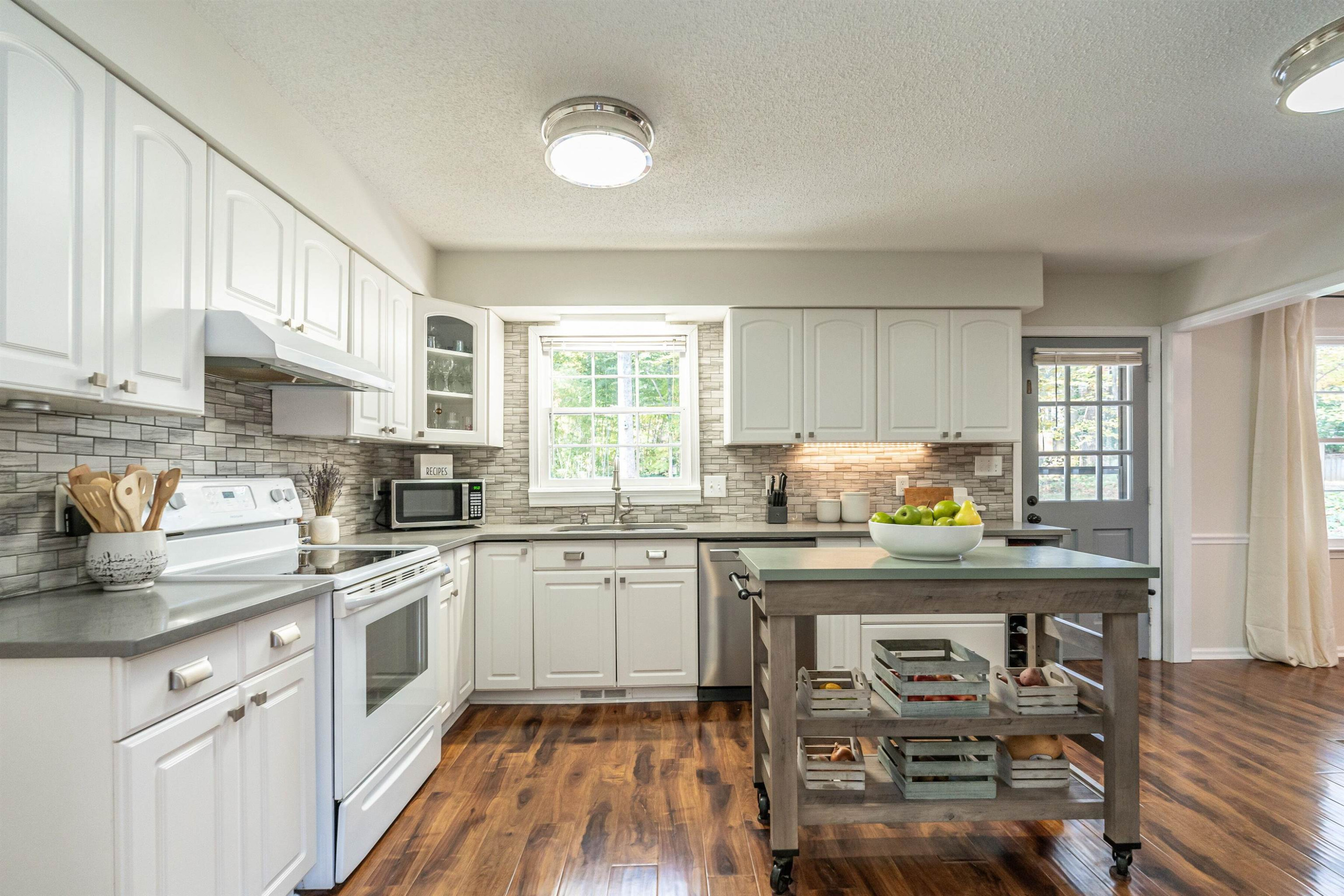 4305 Old Colony Road Raleigh, NC 27613 - Photo 13 of 33 a kitchen with stainless steel appliances granite countertop a stove top oven a sink dishwasher and white cabinets with wooden floor
