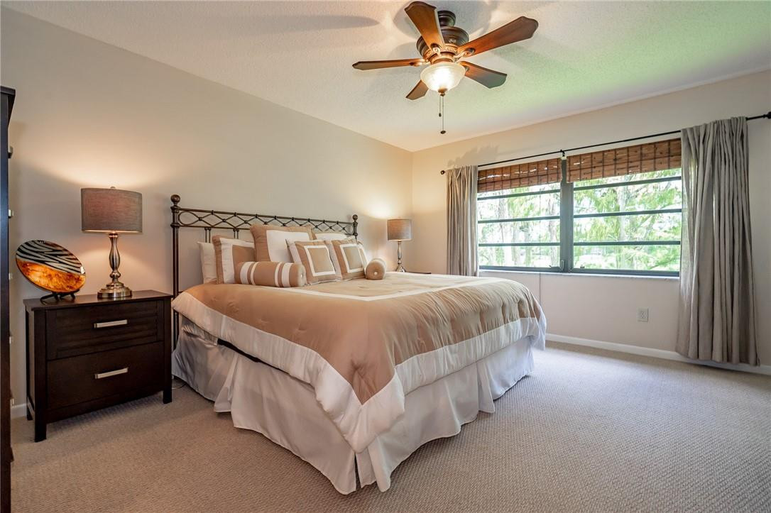 21650 Juego Circle, Unit 24F Boca Raton, FL 33433 - Photo 14 of 24 a spacious bedroom with a bed and a chandelier