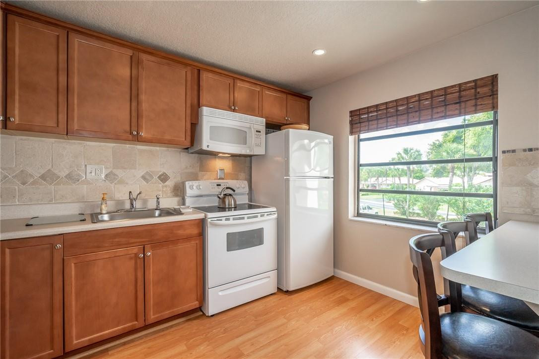 21650 Juego Circle, Unit 24F Boca Raton, FL 33433 - Photo 3 of 24 a kitchen with stainless steel appliances granite countertop a stove a sink dishwasher a refrigerator white cabinets with wooden floor