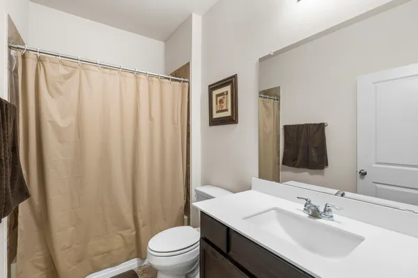 a bathroom with a sink a toilet and shower curtain