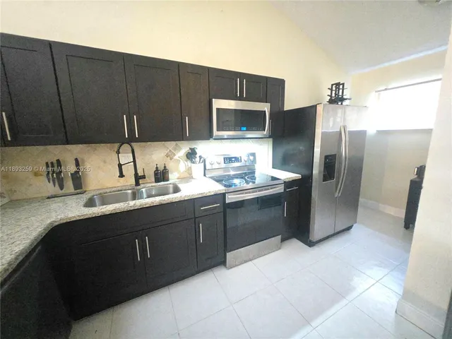 a kitchen with a sink refrigerator and microwave