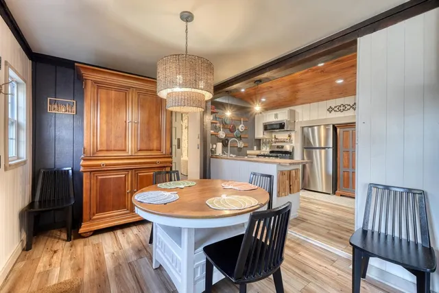 a kitchen with stainless steel appliances granite countertop a kitchen island hardwood floor sink stove dining table and chairs