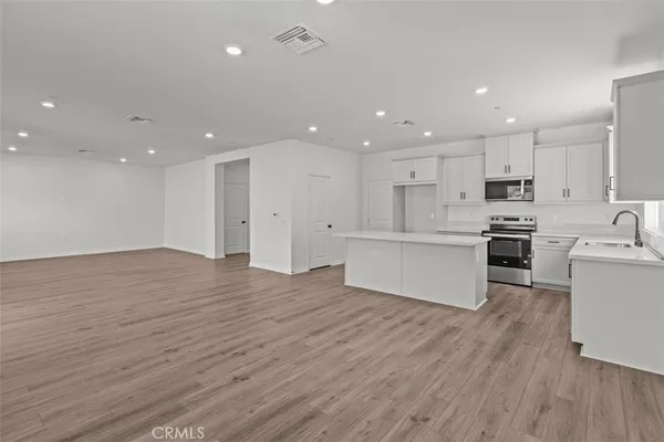 a view of kitchen with kitchen island wooden floors appliances and cabinets