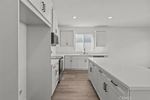 a kitchen with white cabinets appliances and a sink