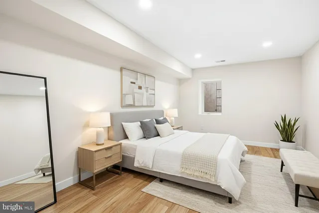 a bedroom with a bed and a potted plant on the dresser