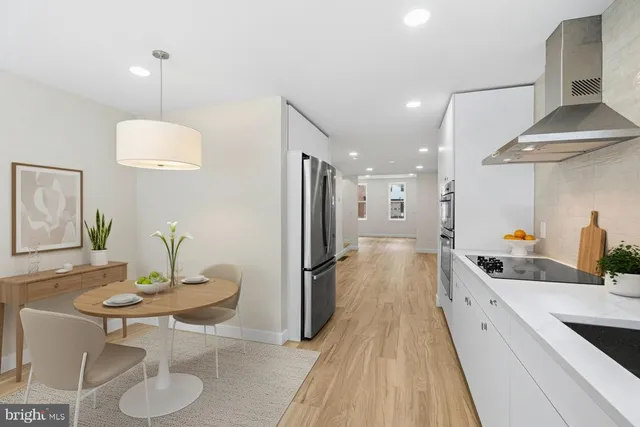 a kitchen with stainless steel appliances a dining table chairs and sink