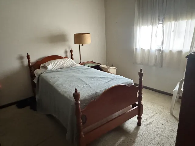 a bed sitting in a bedroom next to a window and lamp