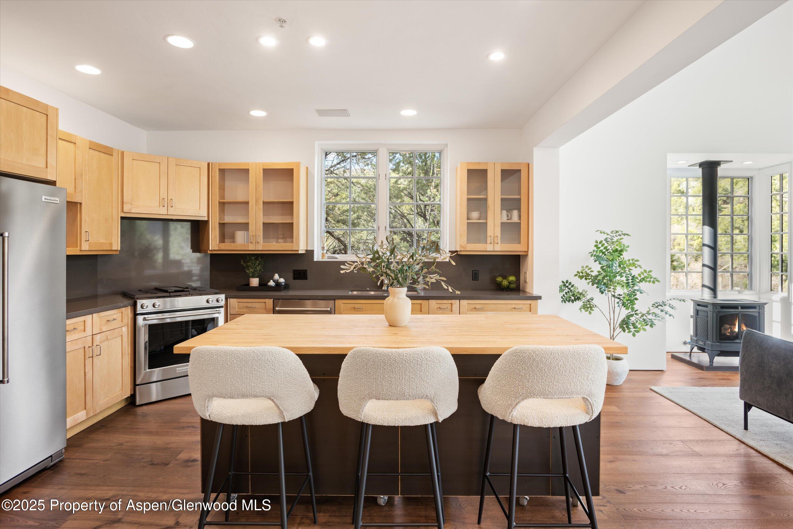 a kitchen with stainless steel appliances granite countertop a kitchen island a table and chairs in it