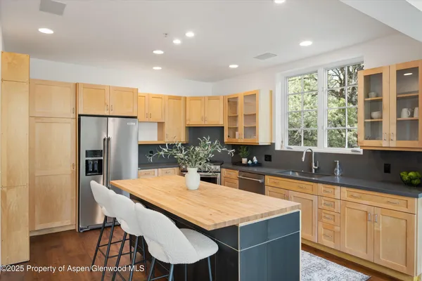 a kitchen with stainless steel appliances granite countertop a table chairs sink refrigerator and cabinets