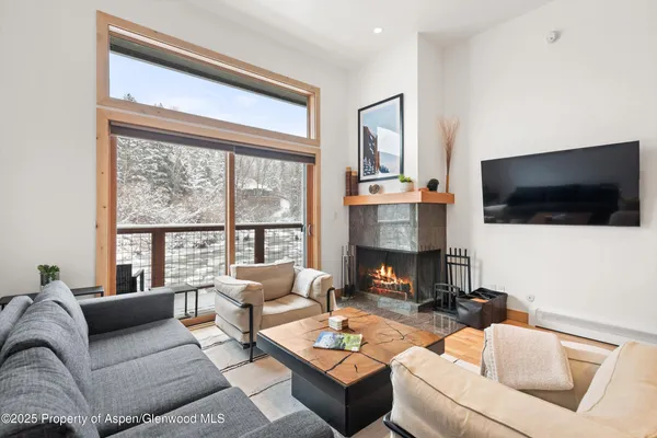 a living room with furniture a flat screen tv and a large window