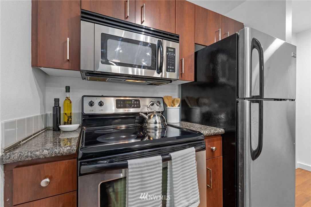 108 5th Avenue South, Unit 710 Seattle, WA 98104 - Photo 2 of 22 a kitchen with stainless steel appliances granite countertop a stove microwave and refrigerator