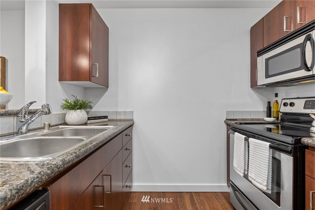 108 5th Avenue South, Unit 710 Seattle, WA 98104 - Photo 3 of 22 a kitchen with granite countertop a sink stove and cabinets