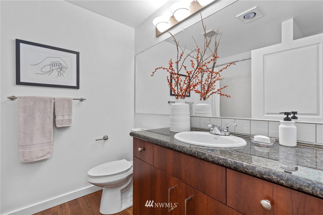 108 5th Avenue South, Unit 710 Seattle, WA 98104 - Photo 7 of 22 a bathroom with a granite countertop sink a toilet and a mirror