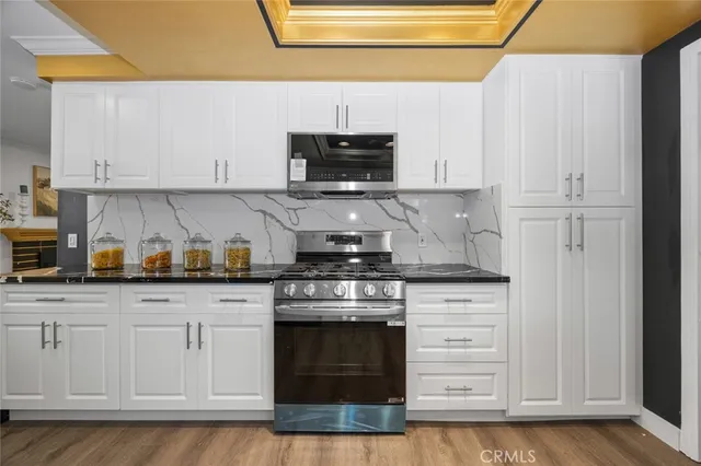 a kitchen with granite countertop white cabinets and stainless steel appliances