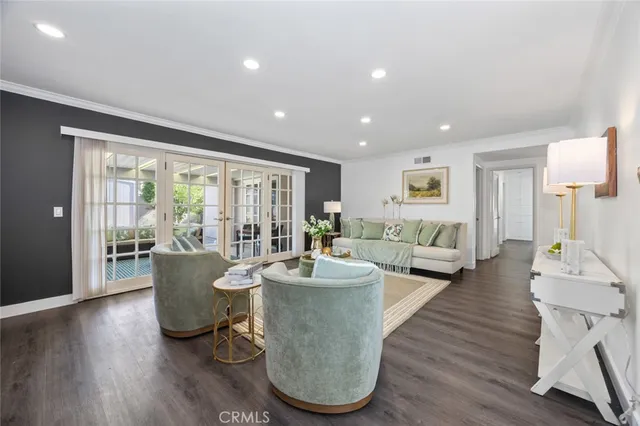 a living room with couches and a dining table with wooden floor