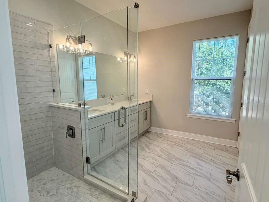 4606 West Fig Street, Unit 2 Tampa, FL 33609 - Photo 17 of 26 a bathroom with a double vanity sink a large mirror and shower
