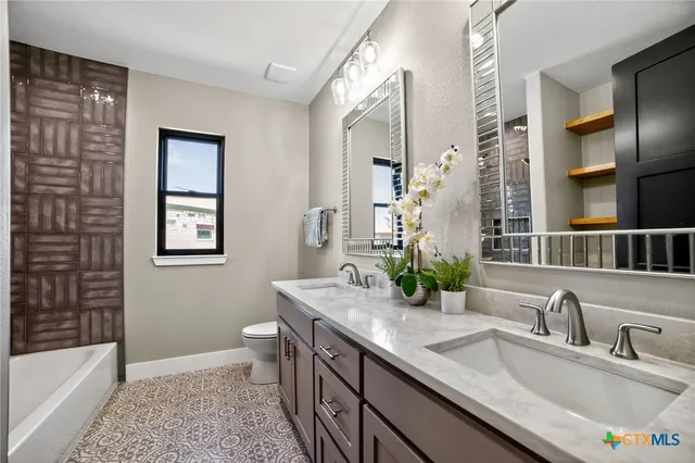 a bathroom with a granite countertop sink a toilet a mirror and shower