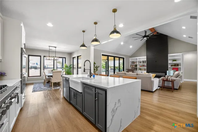 a large kitchen with kitchen island a stove a sink a dining table and chairs with wooden floor