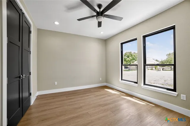 an empty room with wooden floor and windows