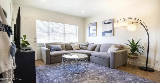 a living room with furniture a large window and a potted plant