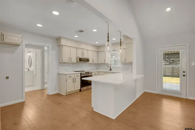 a large kitchen with stainless steel appliances granite countertop a sink and a stove top oven