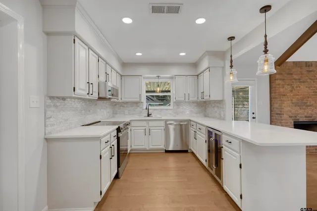 a large white kitchen with stainless steel appliances granite countertop a sink and cabinets