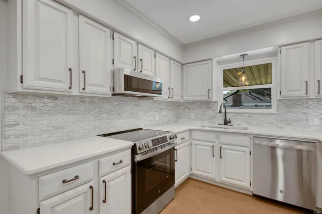 a kitchen with white cabinets sink and stainless steel appliances