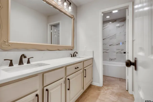 a bathroom with a double vanity sink a mirror and a bathtub