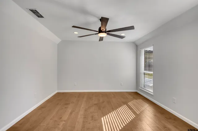 an empty room with windows and fan