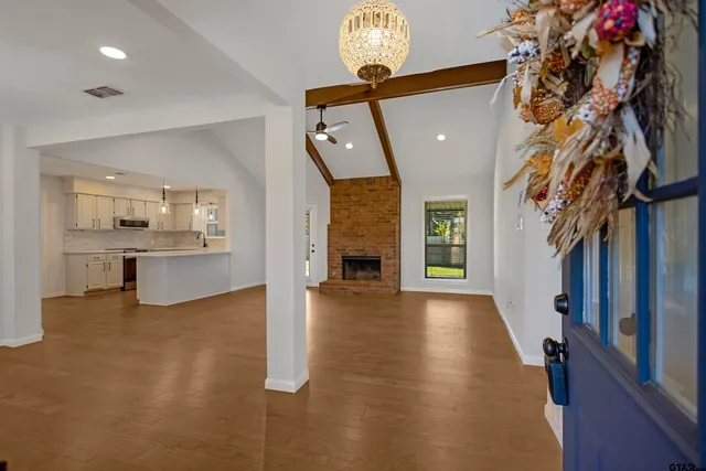 a view of a hallway to a livingroom with furniture wooden floor a fireplace and windows