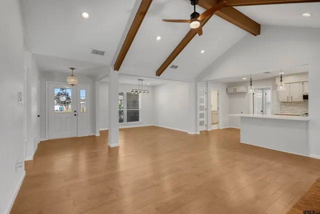a view of an empty room with kitchen and window