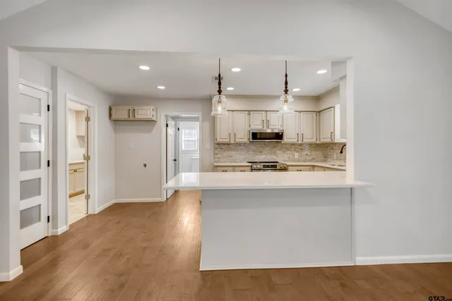 a large kitchen with stainless steel appliances kitchen island a large counter top and a refrigerator