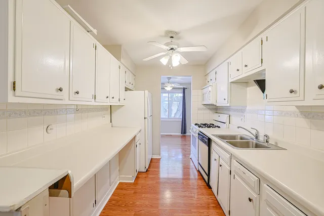 a kitchen with kitchen island granite countertop a sink and white cabinets