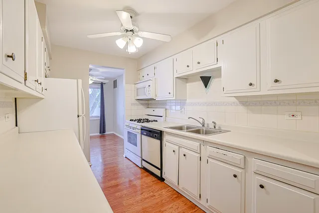 a kitchen with granite countertop white cabinets and white appliances