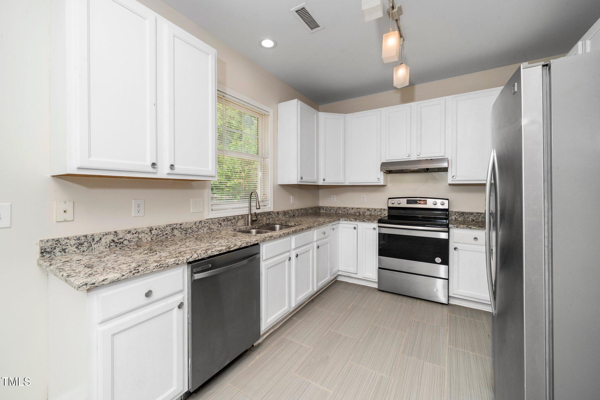 248 Inkster Cove Raleigh, NC 27603 - Photo 21 of 32 a kitchen with granite countertop white cabinets and white appliances