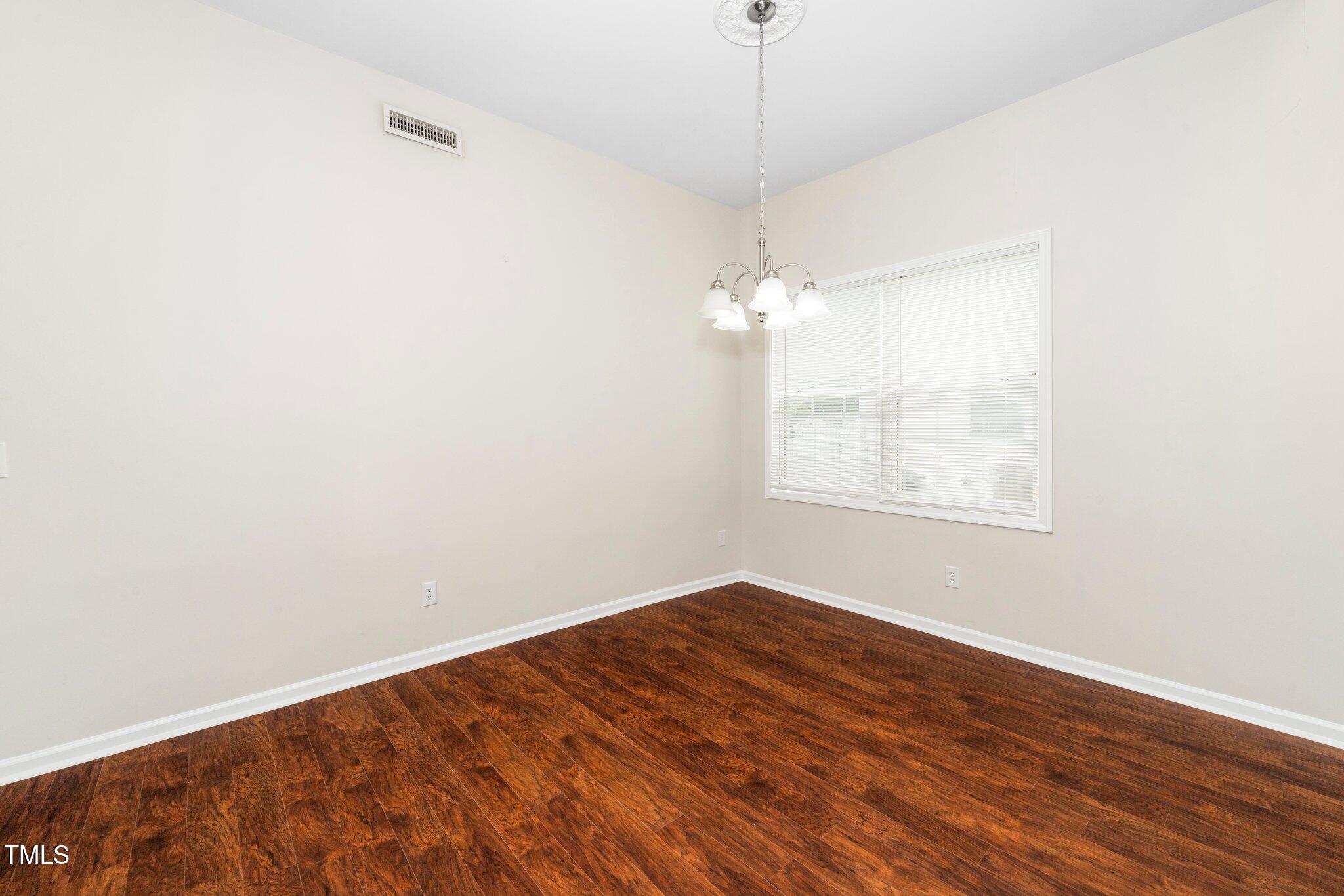 248 Inkster Cove Raleigh, NC 27603 - Photo 10 of 32 an empty room with wooden floor chandelier fan and windows