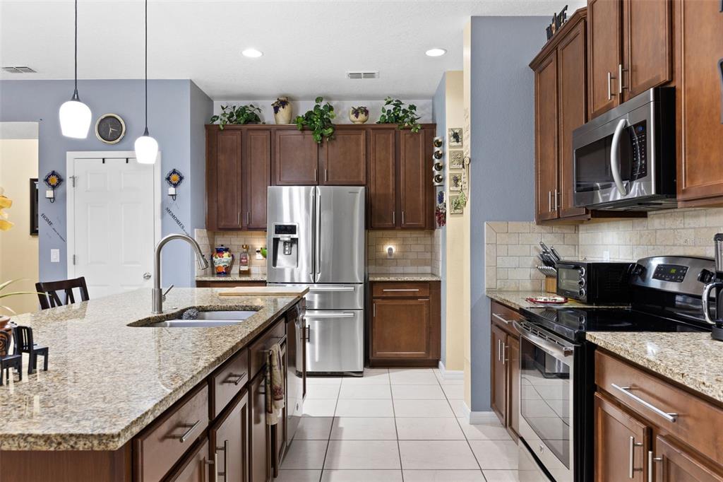 3409 Brant Street St. Cloud, FL 34772 - Photo 11 of 36 a kitchen with stainless steel appliances granite countertop a refrigerator a stove a sink and a microwave