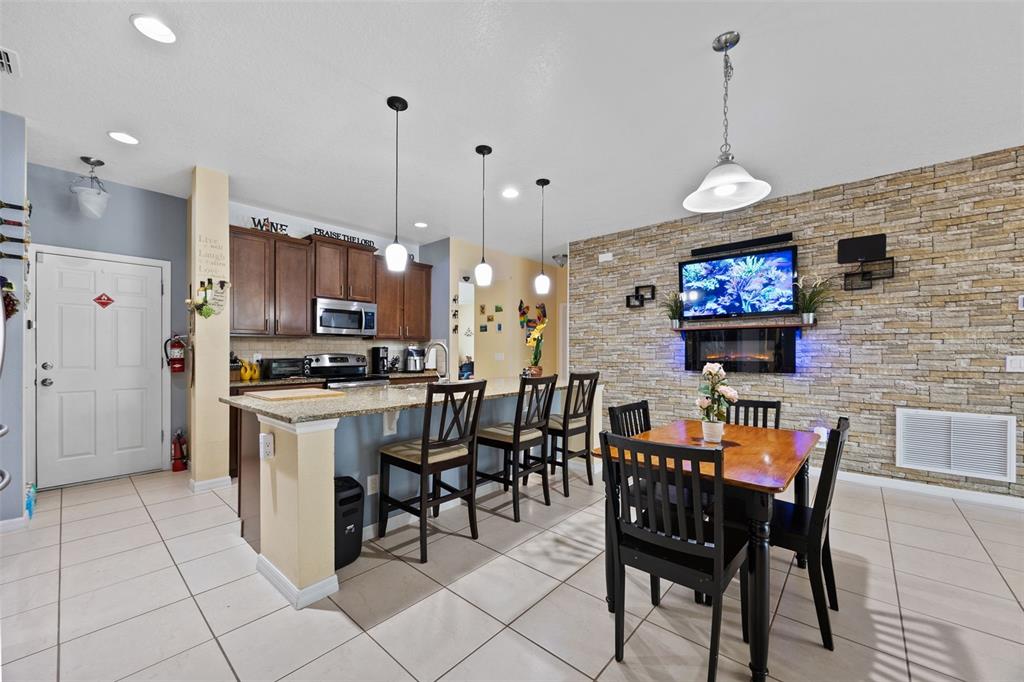 3409 Brant Street St. Cloud, FL 34772 - Photo 12 of 36 a kitchen with stainless steel appliances kitchen island granite countertop a dining table chairs and a refrigerator