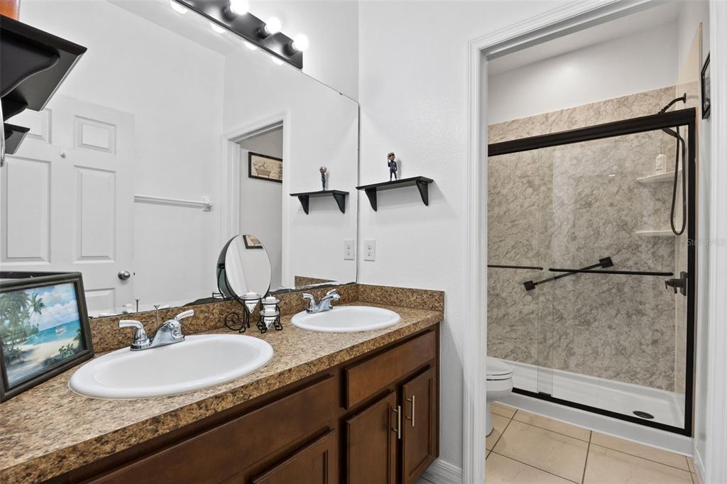 3409 Brant Street St. Cloud, FL 34772 - Photo 22 of 36 a bathroom with a granite countertop sink mirror and a shower