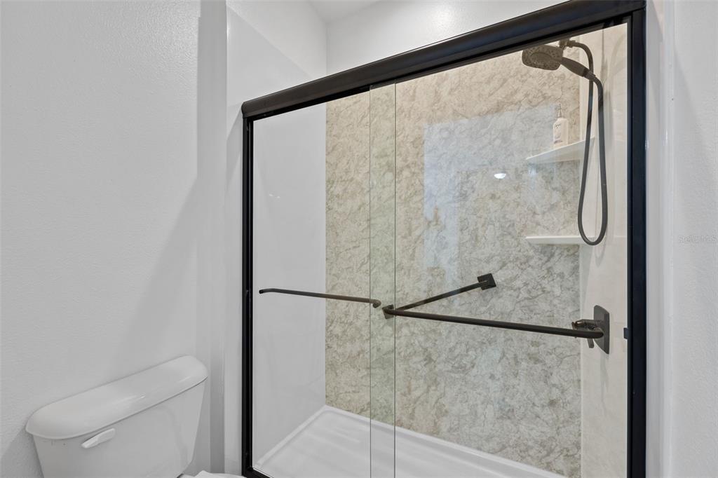 3409 Brant Street St. Cloud, FL 34772 - Photo 23 of 36 a bathroom with a glass shower door and mirror