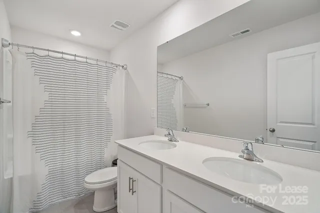 a bathroom with a granite countertop sink a toilet and a mirror