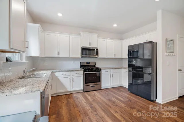 a kitchen with granite countertop a refrigerator and a stove top oven