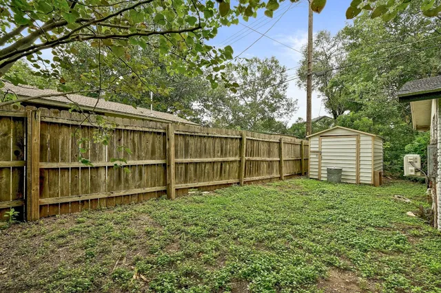 a view of a backyard with a fence and large tree