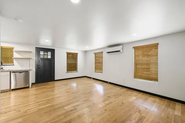 a view of an empty room with window and wooden floor