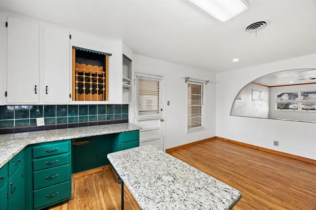 a kitchen with granite countertop white cabinets and window